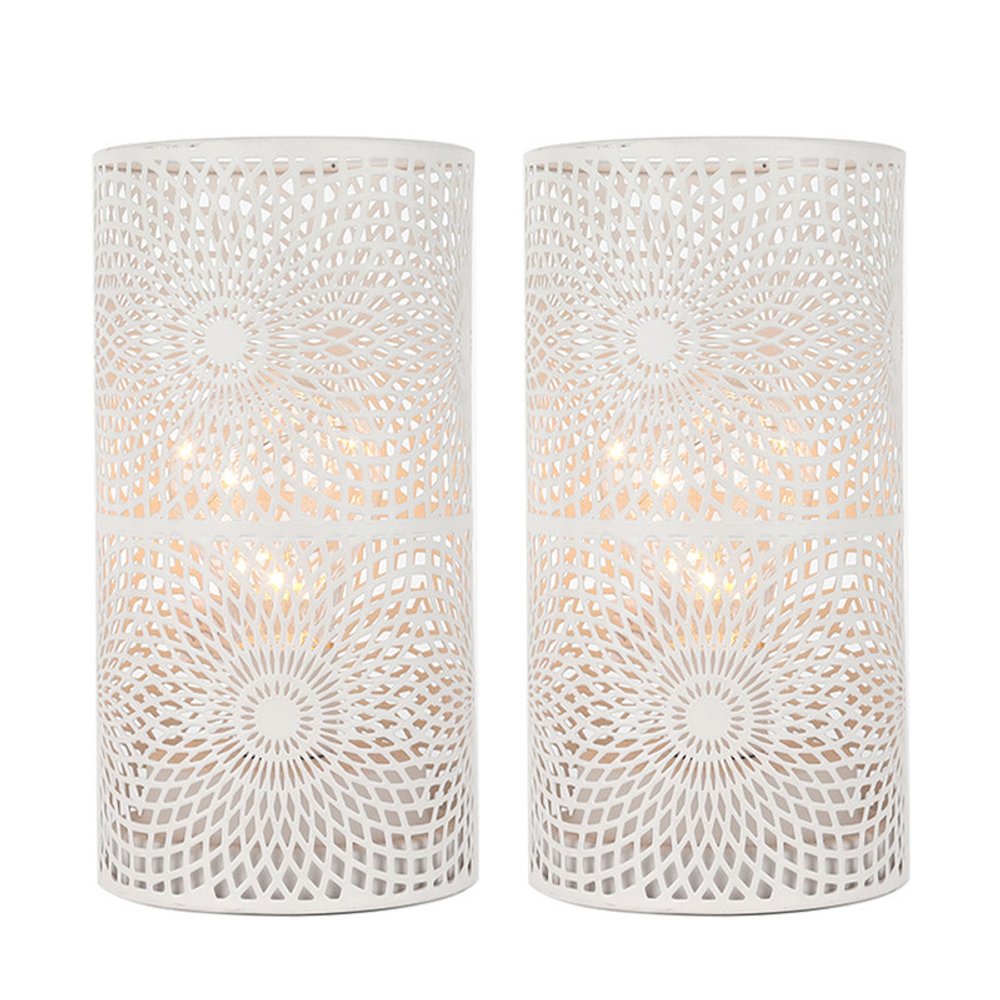 Two white metal pierced geometric cylinder lamps with battery operated lights on a white background.