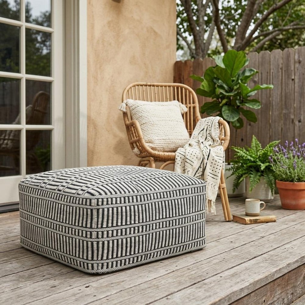20" Black And White Polyester Geometric Outdoor Pouf Ottoman shown outdoors on a patio.