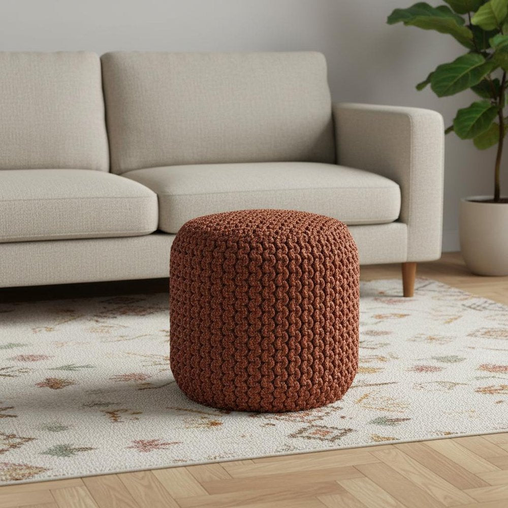 18" Orange Polyester Round Outdoor Pouf Ottoman styled in a furnished interior with a light gray wall on a wood floor.