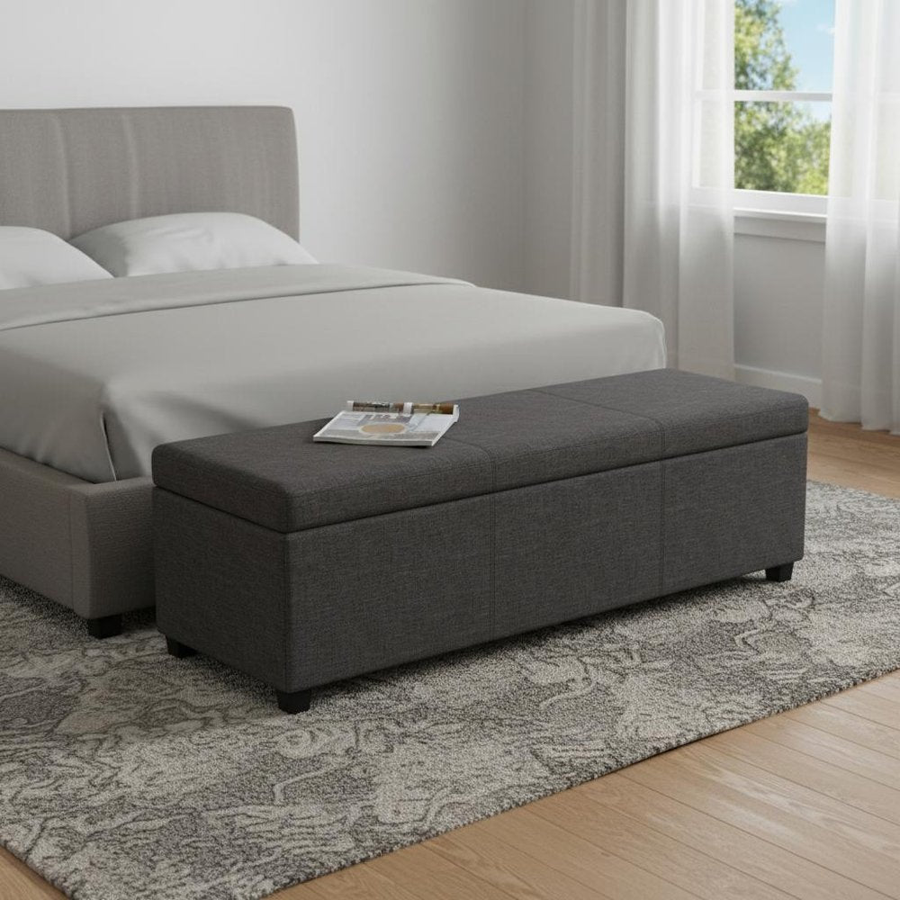 54" Slate Gray and Dark Brown Linen Blend and Solid Wood Upholstered Storage Bench With Flip Top styled in a furnished interior with an off-white wall on a wood floor.