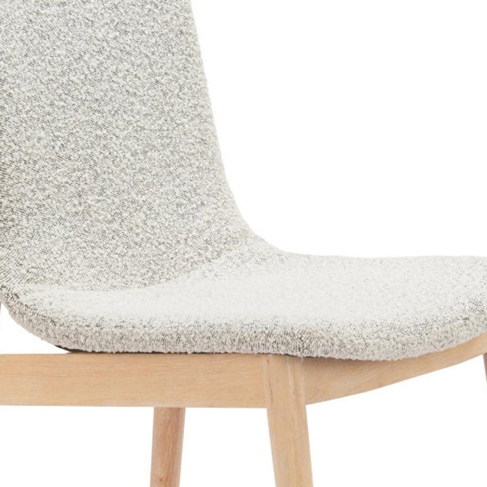 Close-up of a white upholstered dining chair with light wood legs against a white background.