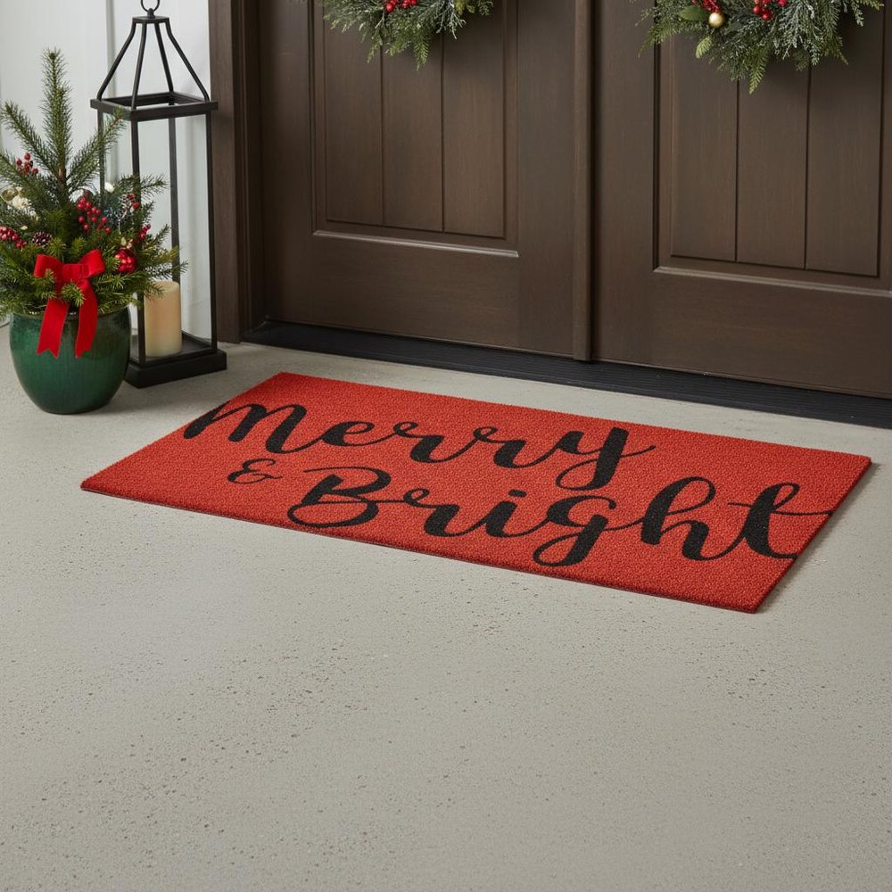 30" X 48" Red And Black Christmas Merry and Bright Outdoor Coir Door Mat styled in a furnished interior with a dark brown wall on a tiled floor.