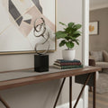 20" Silver And Black Aluminum And Marble Modern Abstract Tabletop Sculpture styled in a furnished interior with a light gray wall on a wood floor.