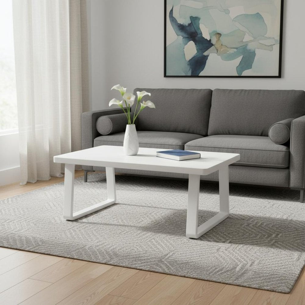43" White Aluminum Outdoor Coffee Table styled in a furnished interior with a light gray wall on a wood floor.