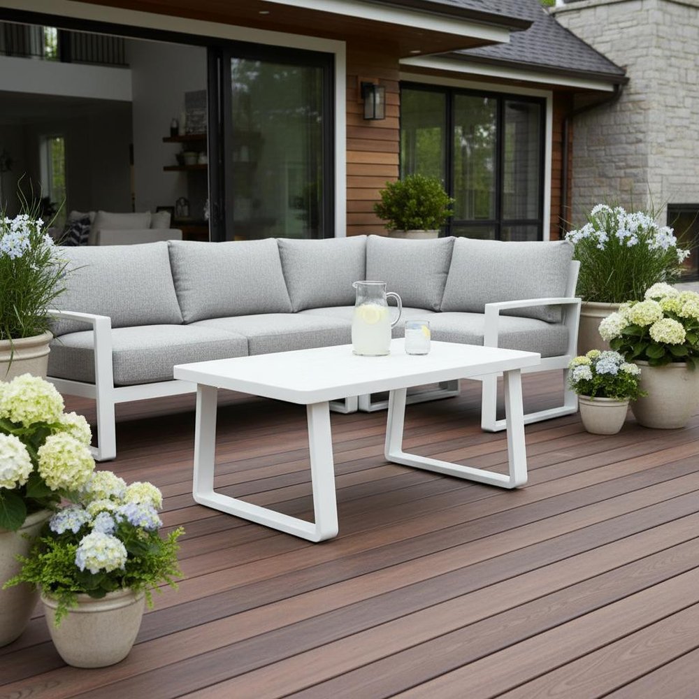43" White Aluminum Outdoor Coffee Table styled in a furnished interior with a black wall on a wood floor.