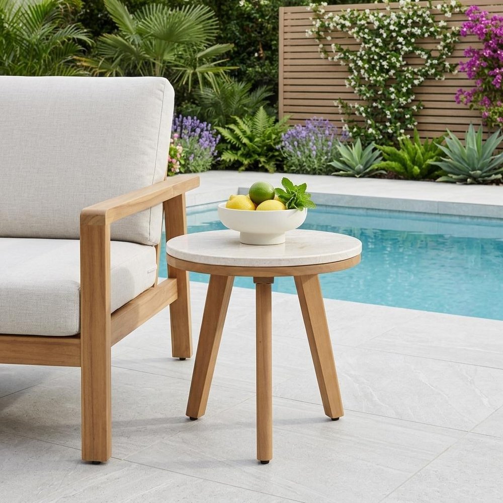 16" Beige and Natural Stone and Solid Wood Round Outdoor Side Table shown outdoors on a patio with greenery.