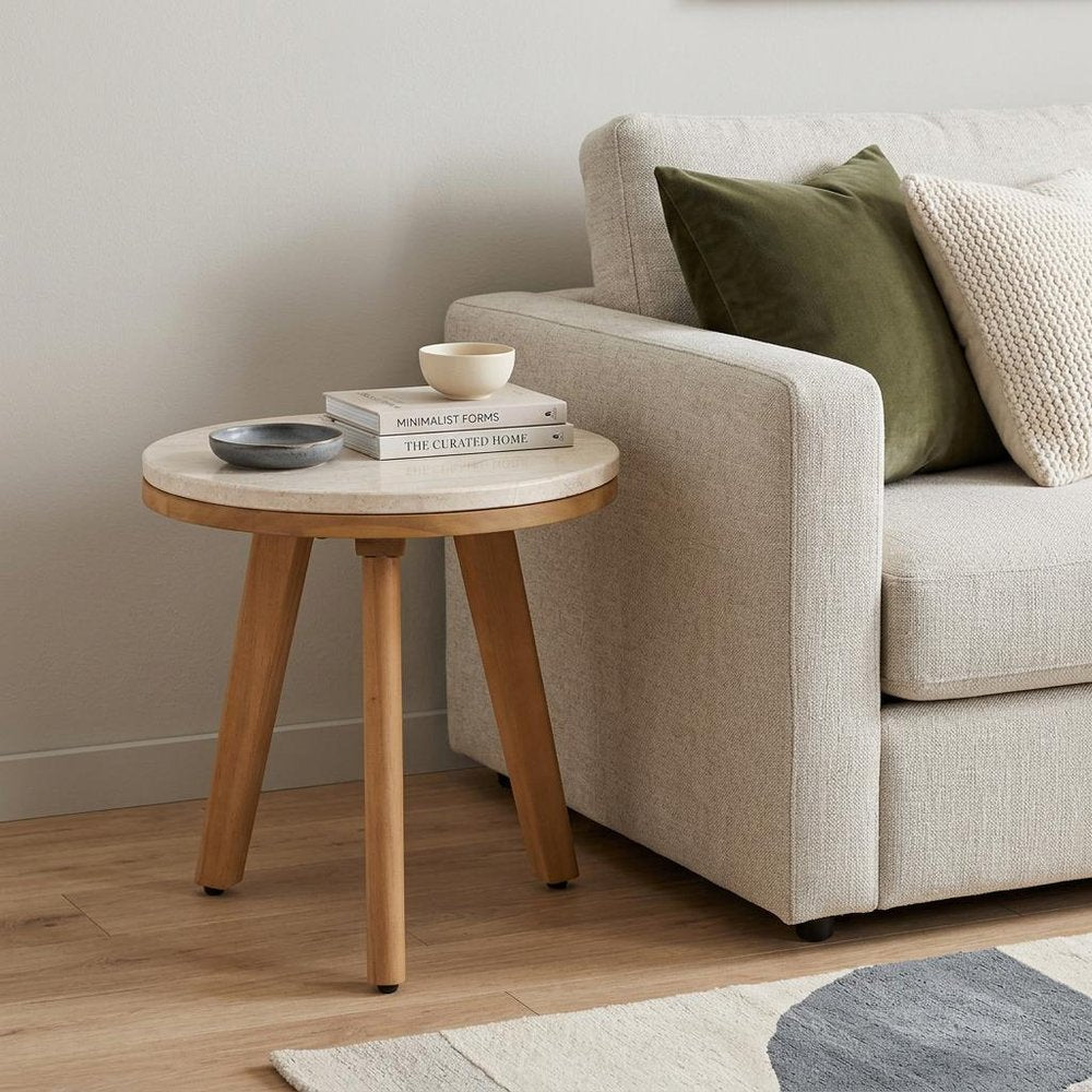 16" Beige and Natural Stone and Solid Wood Round Outdoor Side Table styled in a furnished interior with an off-white wall on a wood floor.