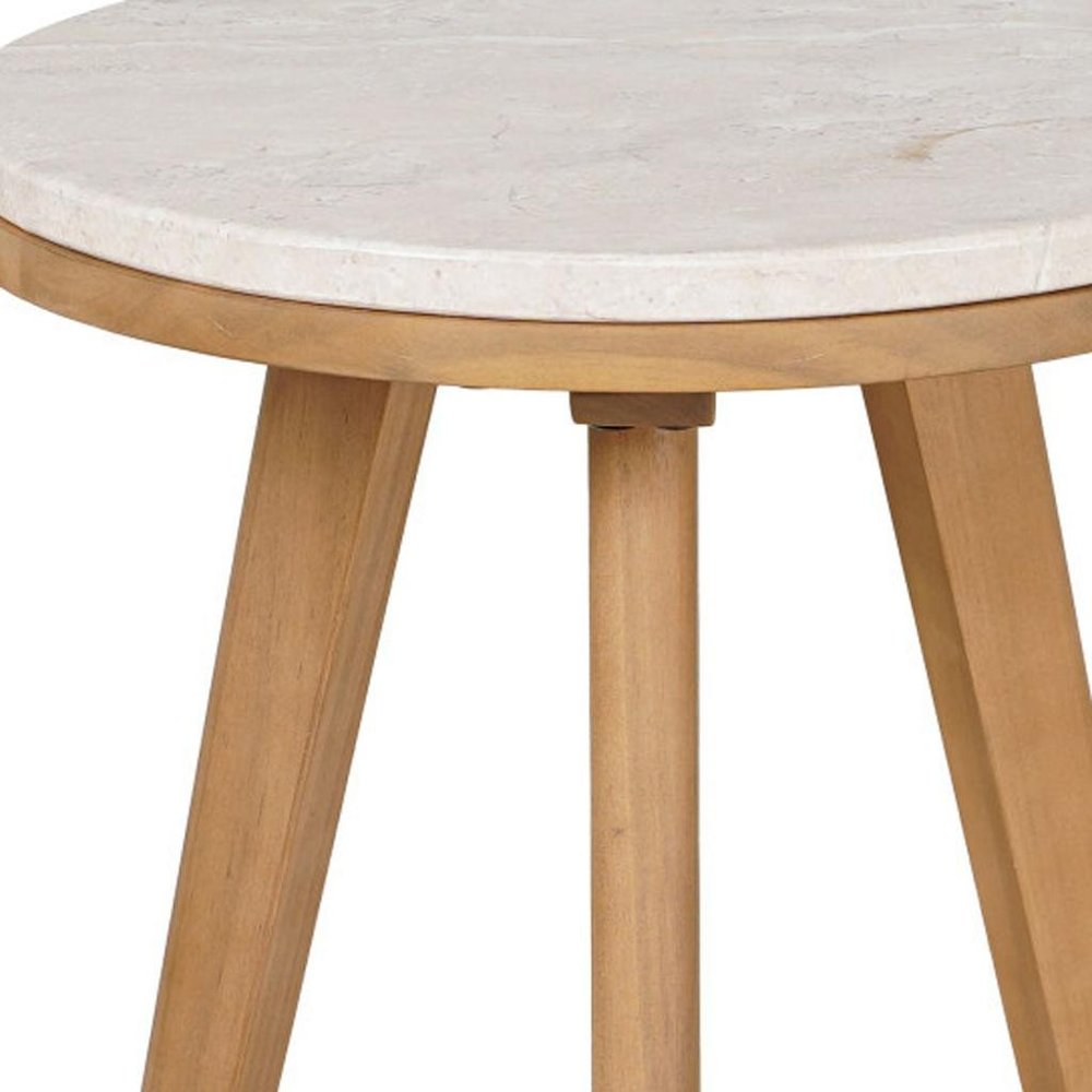 Close-up of a round outdoor side table with a beige marble top and natural wood legs.