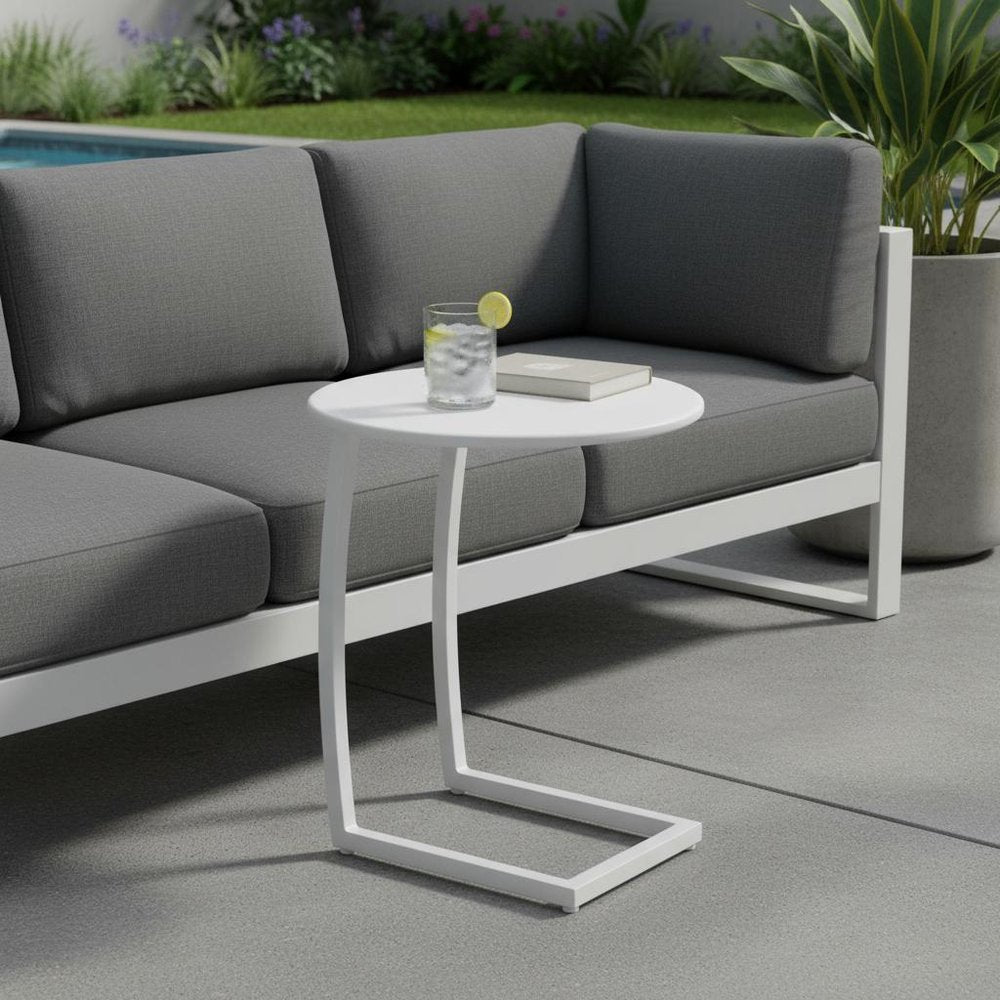 20" White Aluminum Round Outdoor Side Table shown outdoors on a tiled patio with greenery.