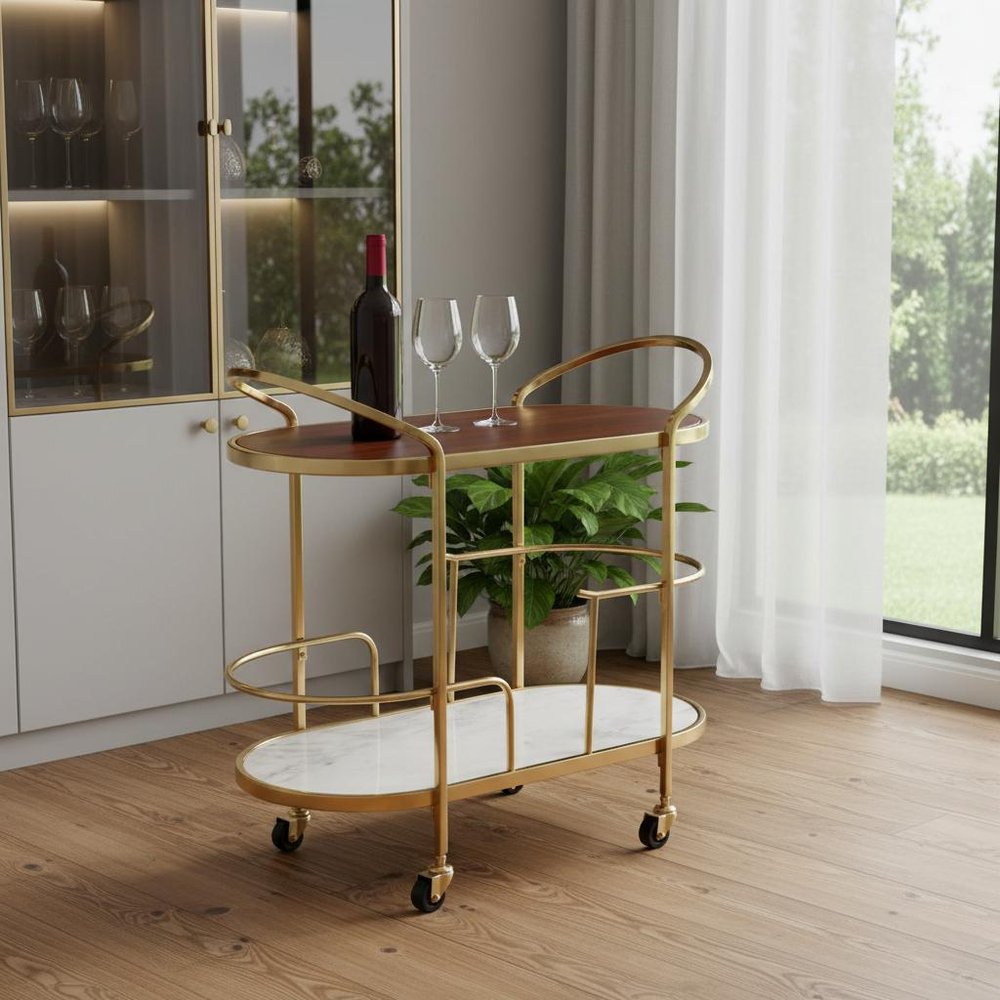 32" Brown Gold And White Iron Solid Wood and Marble Oval Rolling Bar Cart styled in a furnished interior with an off-white wall on a wood floor.