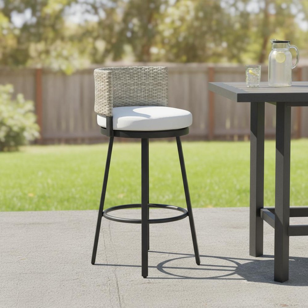 31" Black Natural and White Aluminum And Faux Rattan Swivel Bar Height Bar Chair shown outdoors on a tiled patio with greenery.