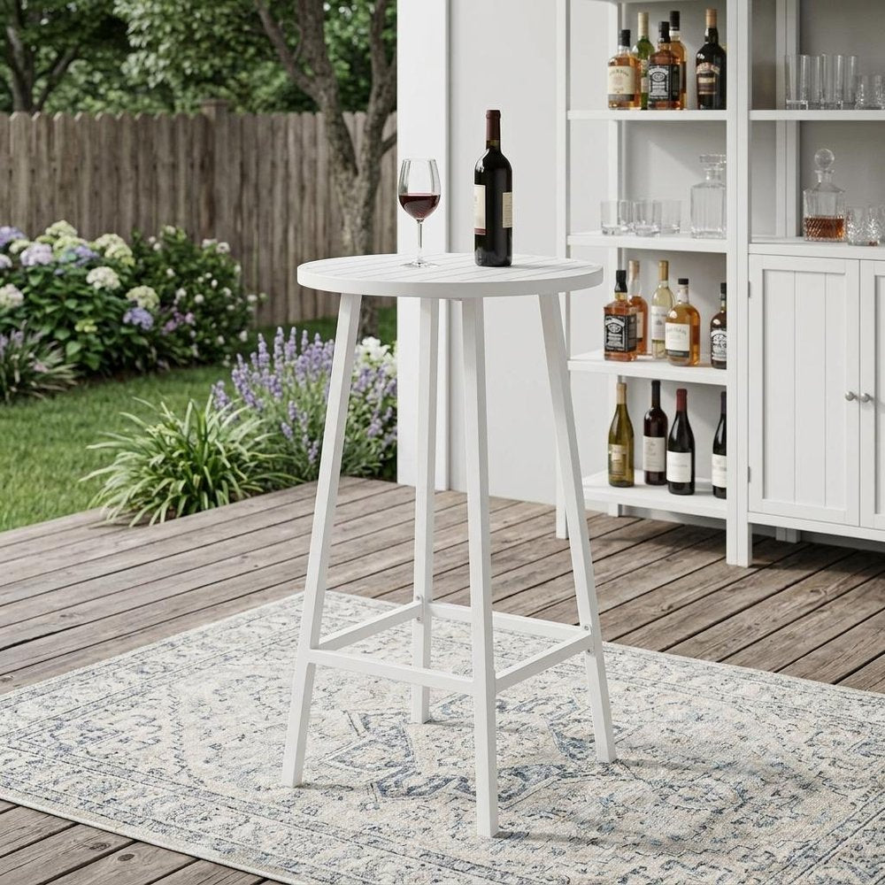 24" White Aluminum Slat Rounded Outdoor Bar Table shown outdoors on a tiled patio with greenery.