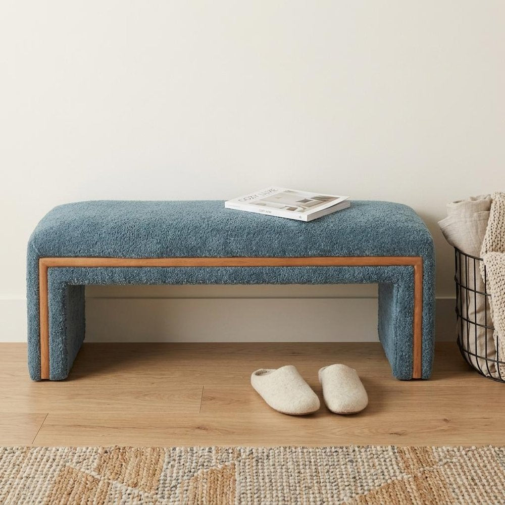56" Blue and Brown Fabric and Solid Wood Upholstered Bench styled in a furnished interior with an off-white wall on a wood floor.