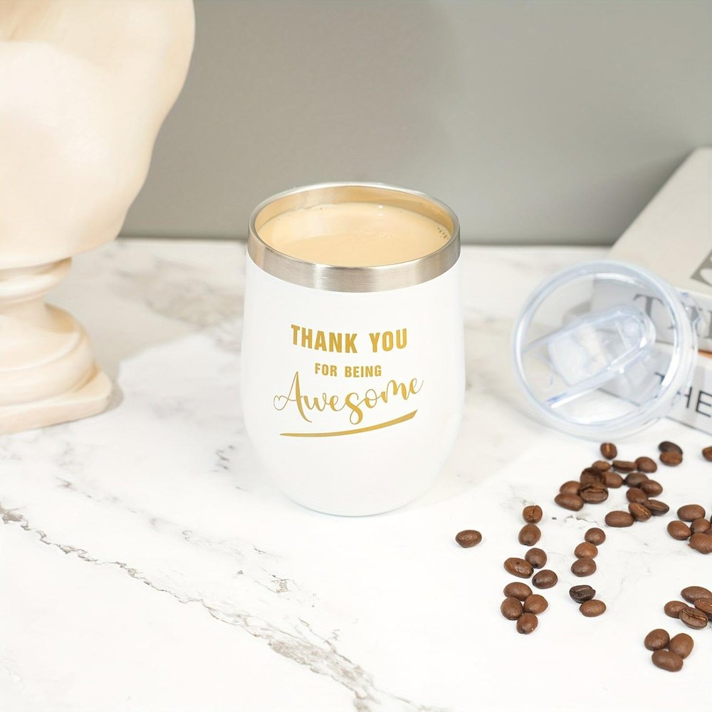 White insulated wine tumbler with gold text that reads "Thank You For Being Awesome" on a marble surface with coffee beans.