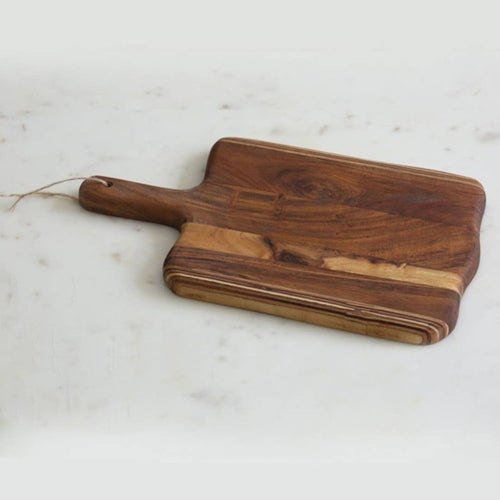 A brown solid wood cutting board with a handle and twine on a white marble surface.