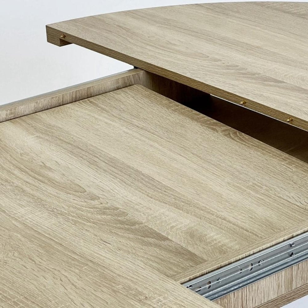 59" Brown and White Wood Oval Cross Legs Coffee Table styled in a furnished interior with an off-white wall on a wood floor.