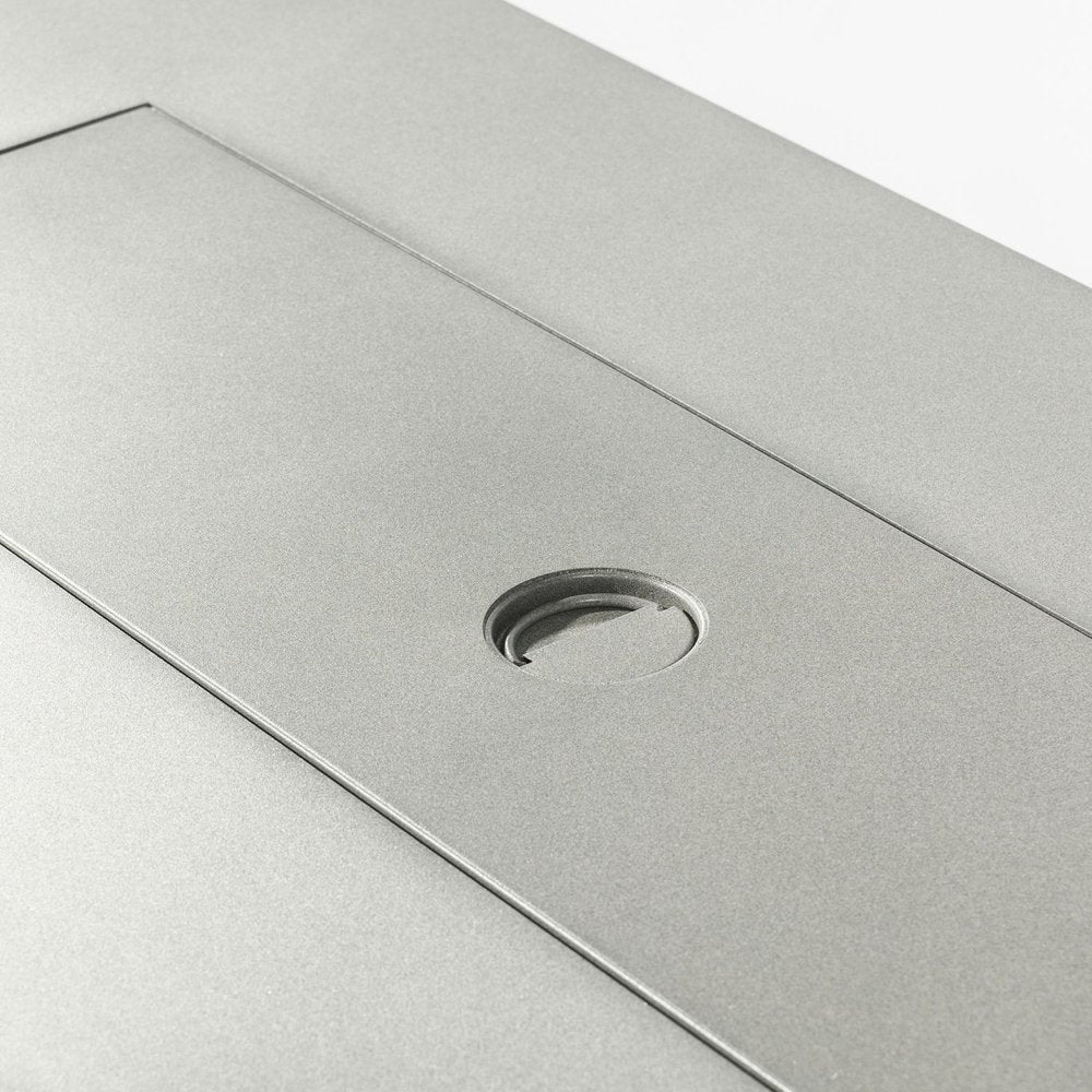 Close-up of a gray steel fire pit with a circular opening and a rectangular cover.