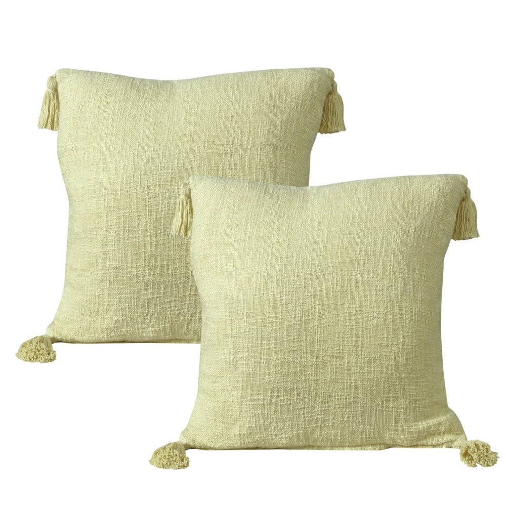 Two yellow textured cotton throw pillows with tassels on a white background.