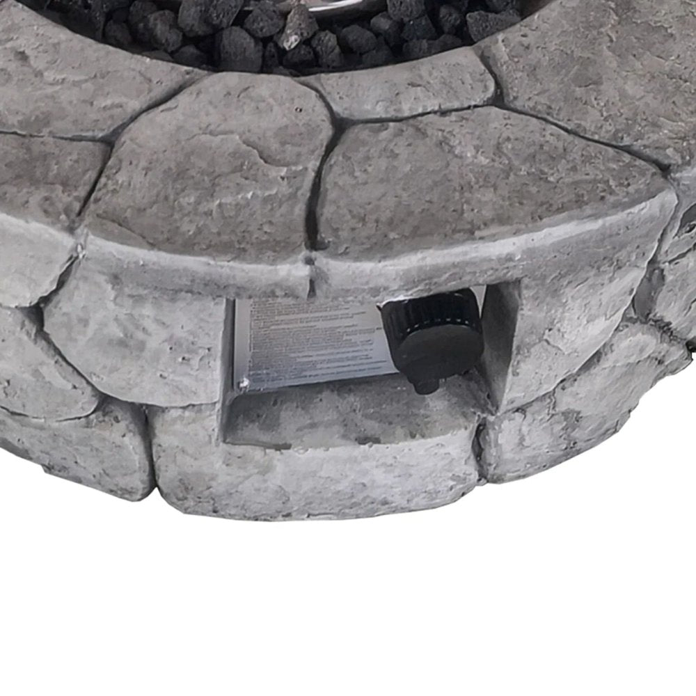 Close-up of a gray stone-look fire pit with a black control knob and a metal label.