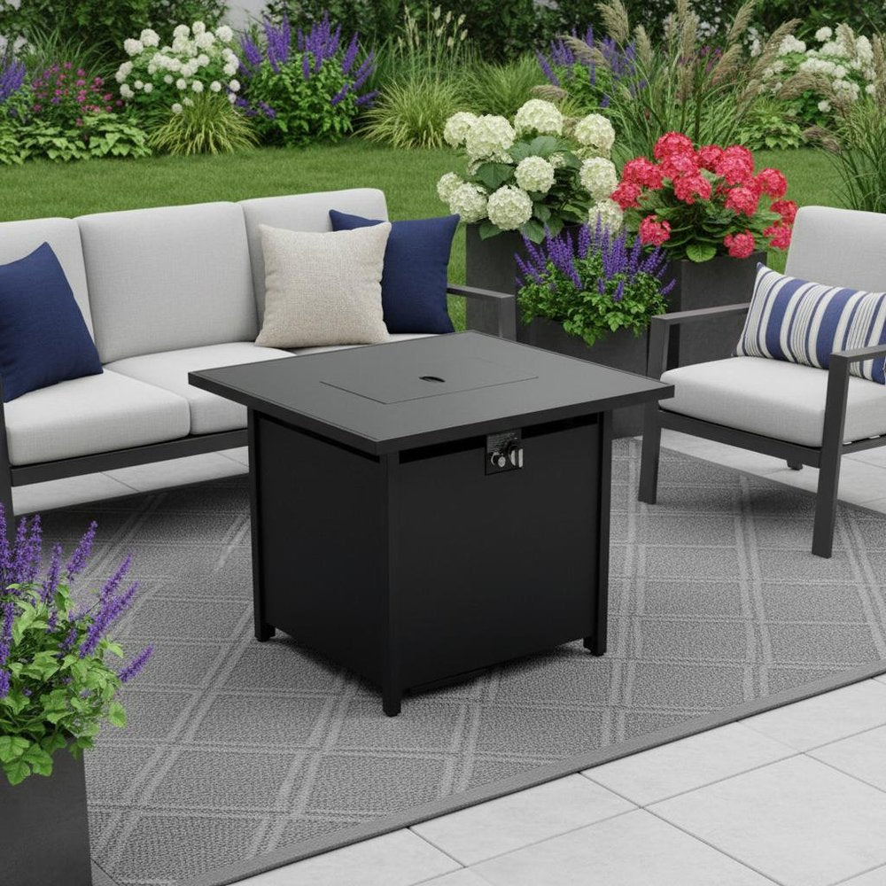 40000 BTU 42" Black Steel Propane Rectangular Fire Pit With Cover shown outdoors on a tiled patio with greenery.