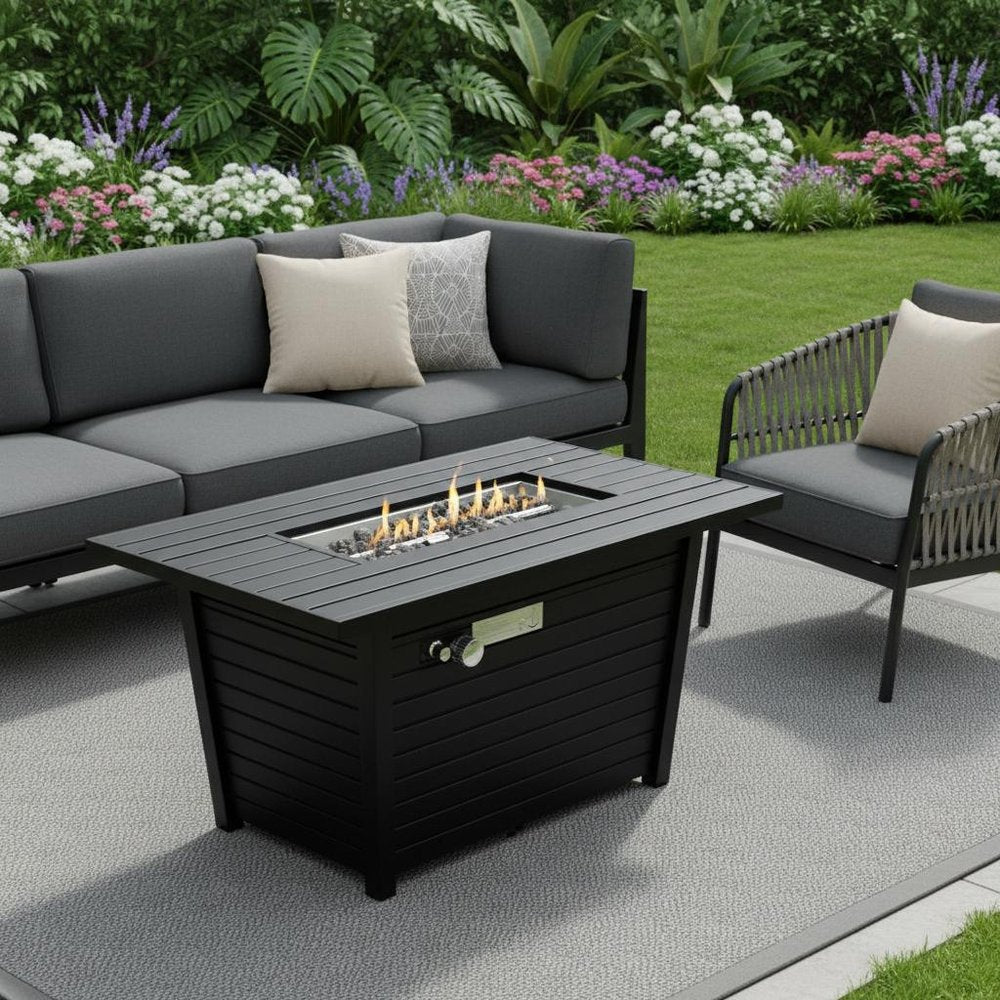 40000 BTU 42" Black Steel Propane Rectangular Fire Pit With Cover shown outdoors on a tiled patio with greenery.