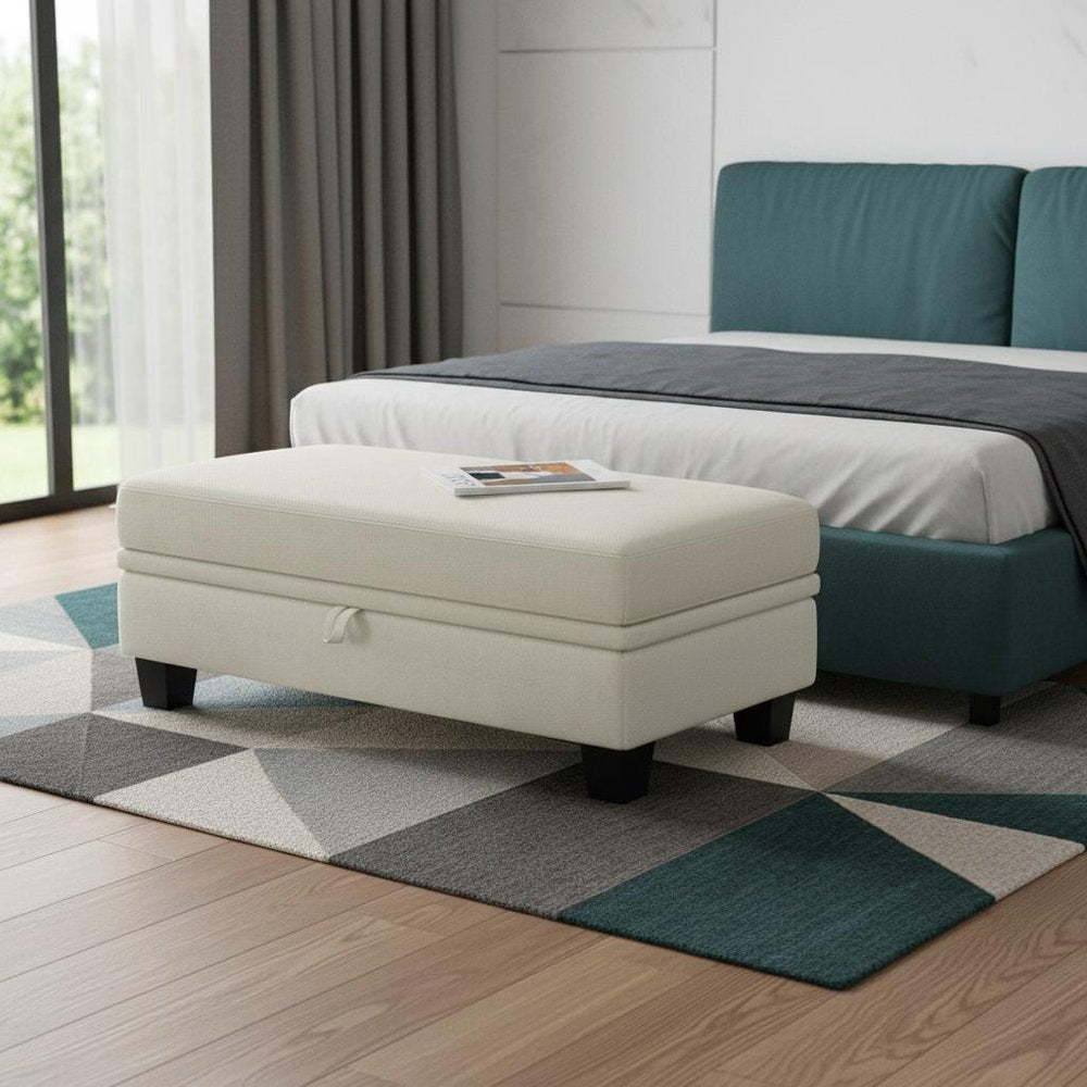 46" Beige And Black Chenille Ottoman With Storage styled in a furnished interior with an off-white wall on a dark wood floor.