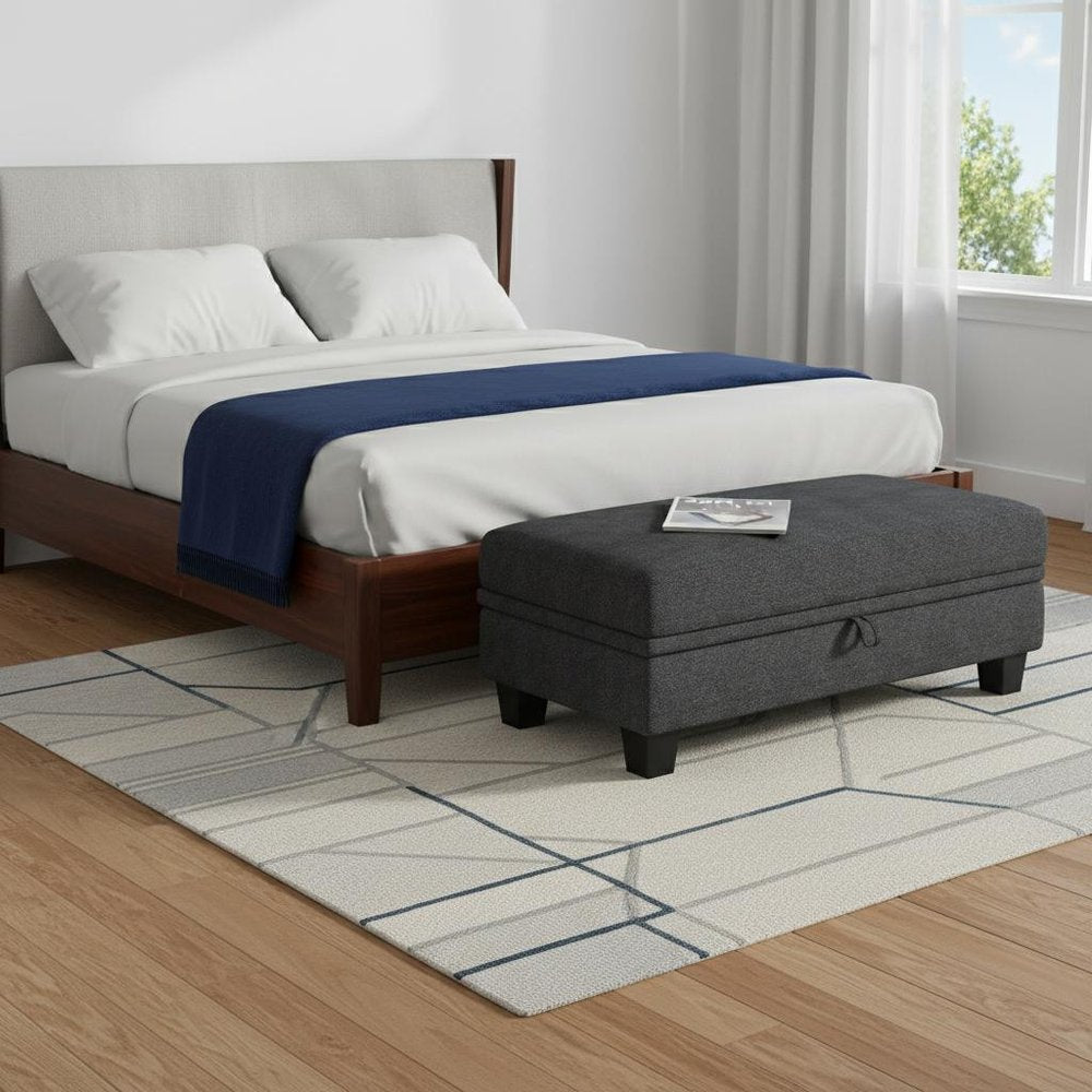 46" Beige And Black Chenille Ottoman With Storage styled in a furnished interior with an off-white wall on a wood floor.