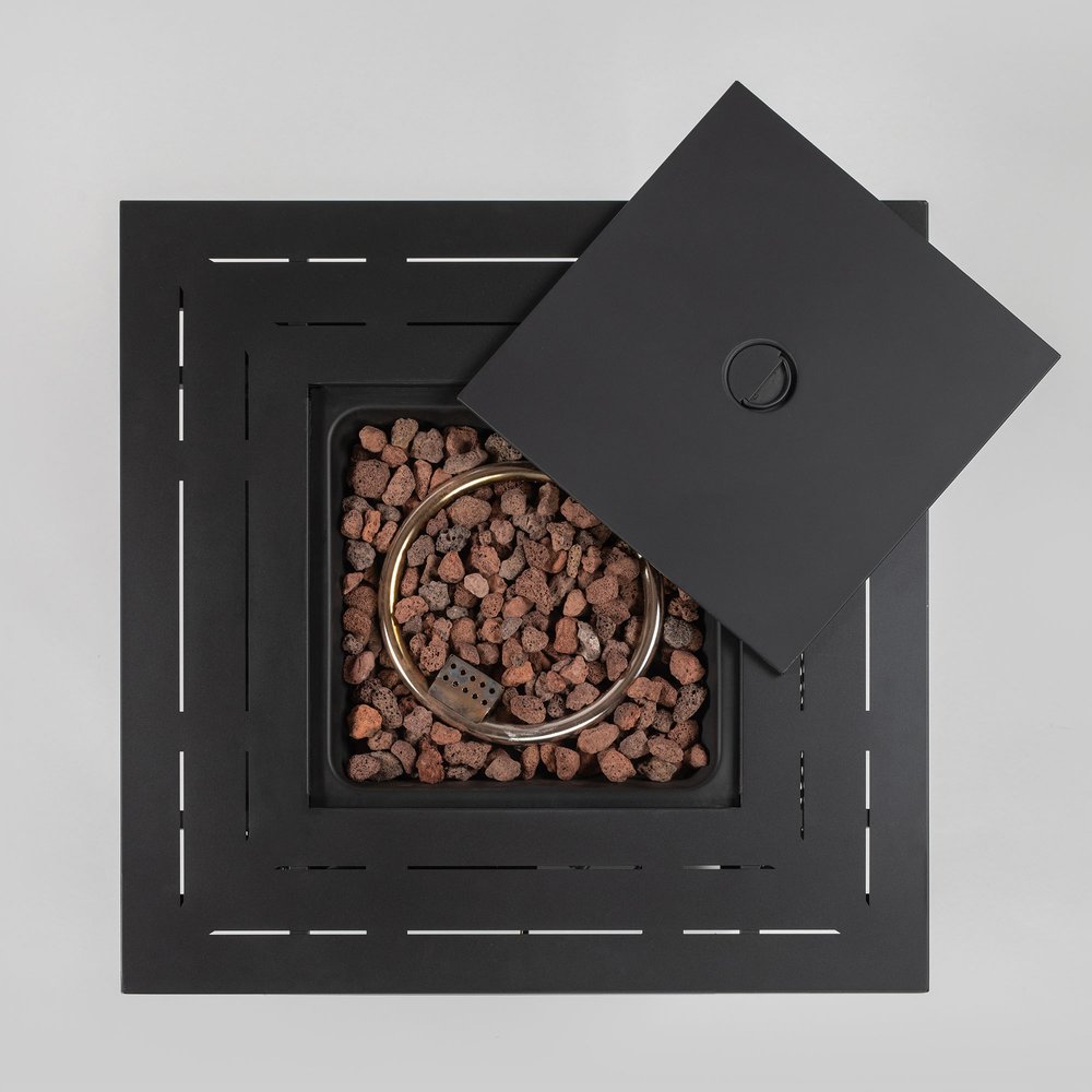 Black square fire pit with lava rocks and a partial lid, set against a light gray background.