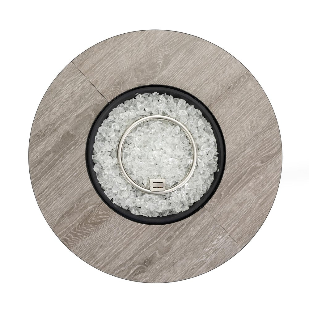 Top view of a round fire pit with a gray wood-look finish, black basin, and clear glass fire media.