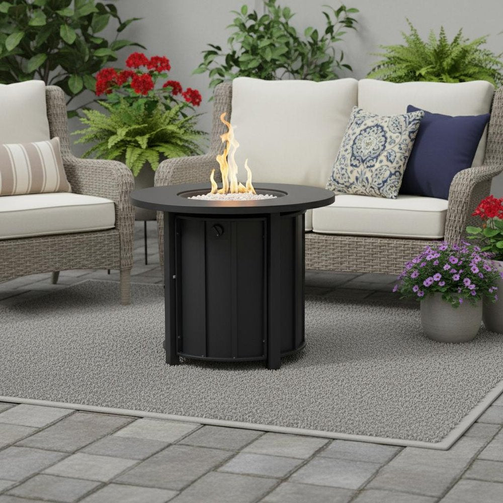 50000 BTU 30" Black Steel Propane Column Fire Pit With Cover shown outdoors on a tiled patio with greenery.