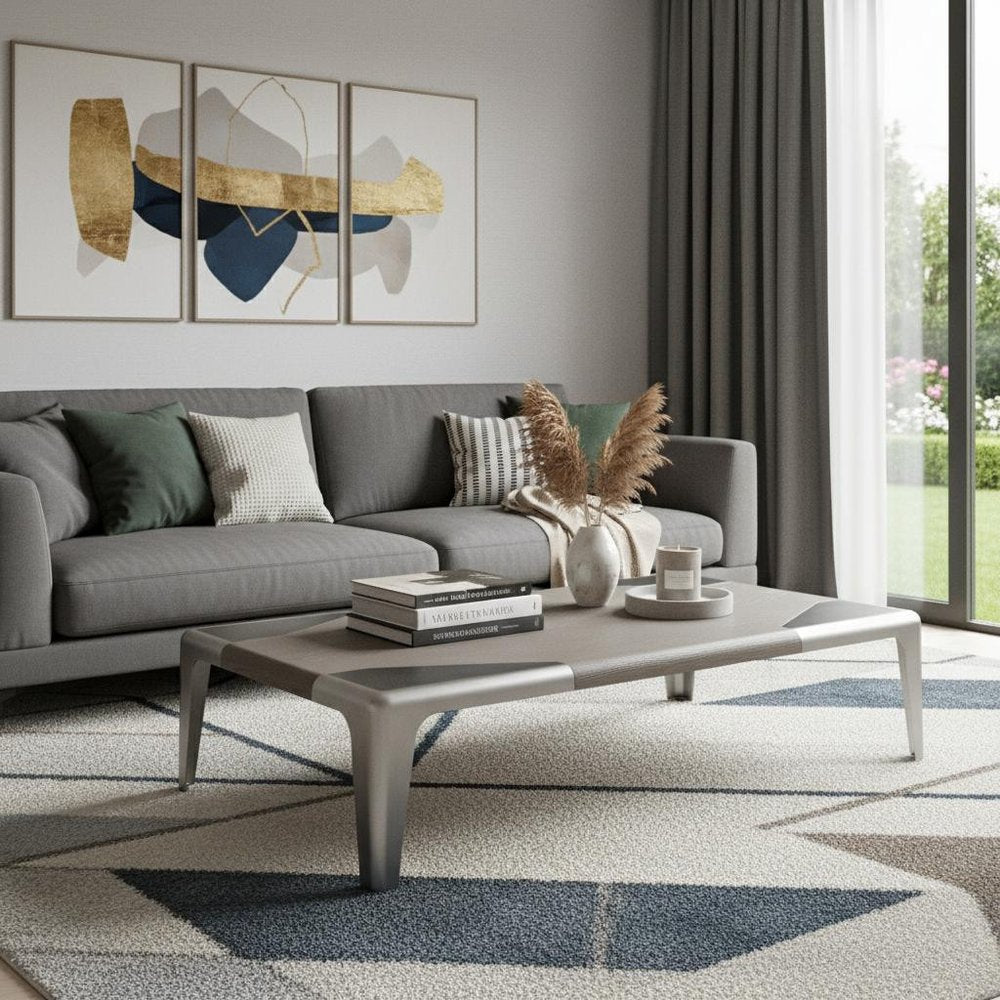 57" Light Gray and Silver Wood and Stainless Steel Coffee Table styled in a furnished interior with a gray wall on a tiled floor.