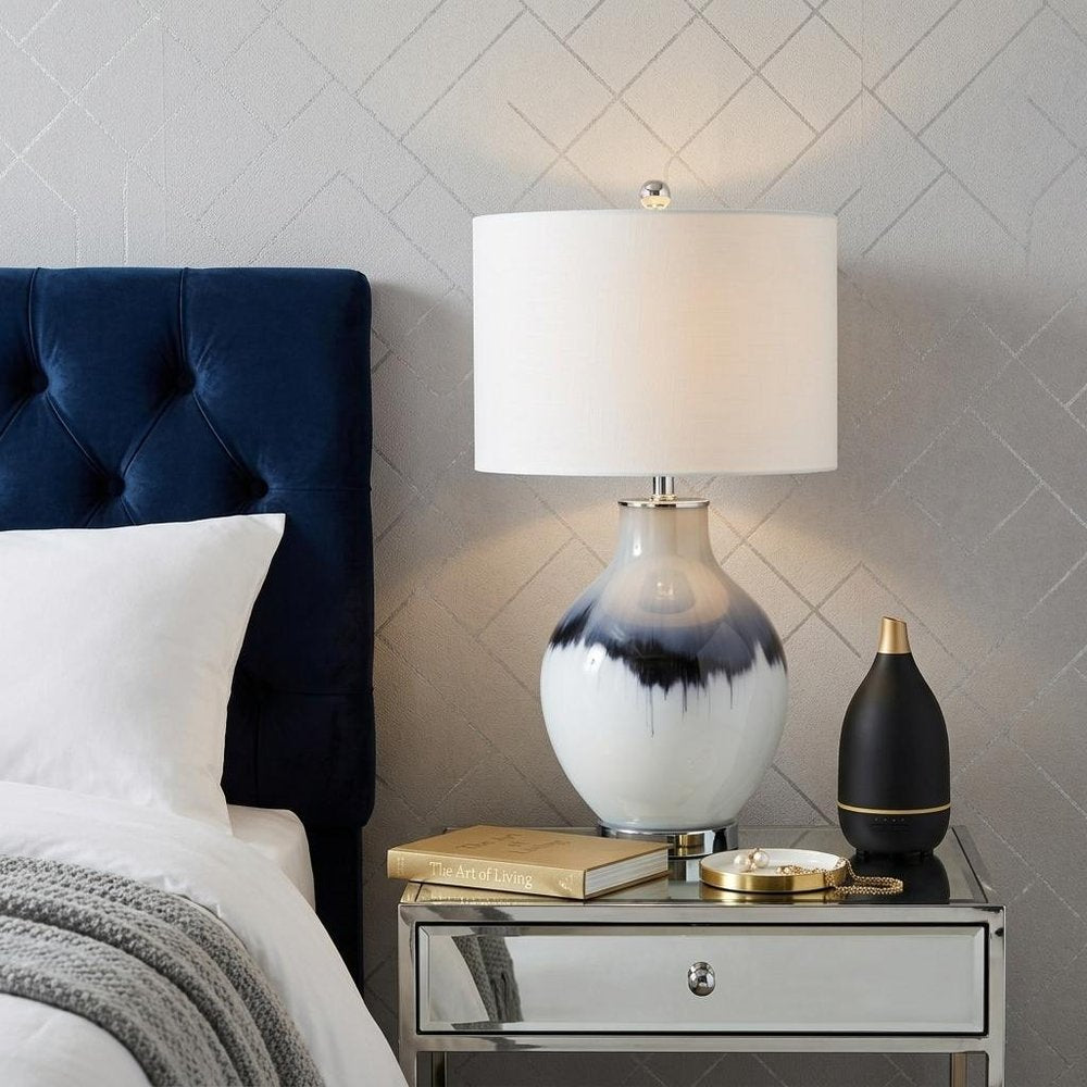 27" Silver Novelty Table Lamp With Globe Shade displayed on a tabletop in a furnished interior against a light gray wall.