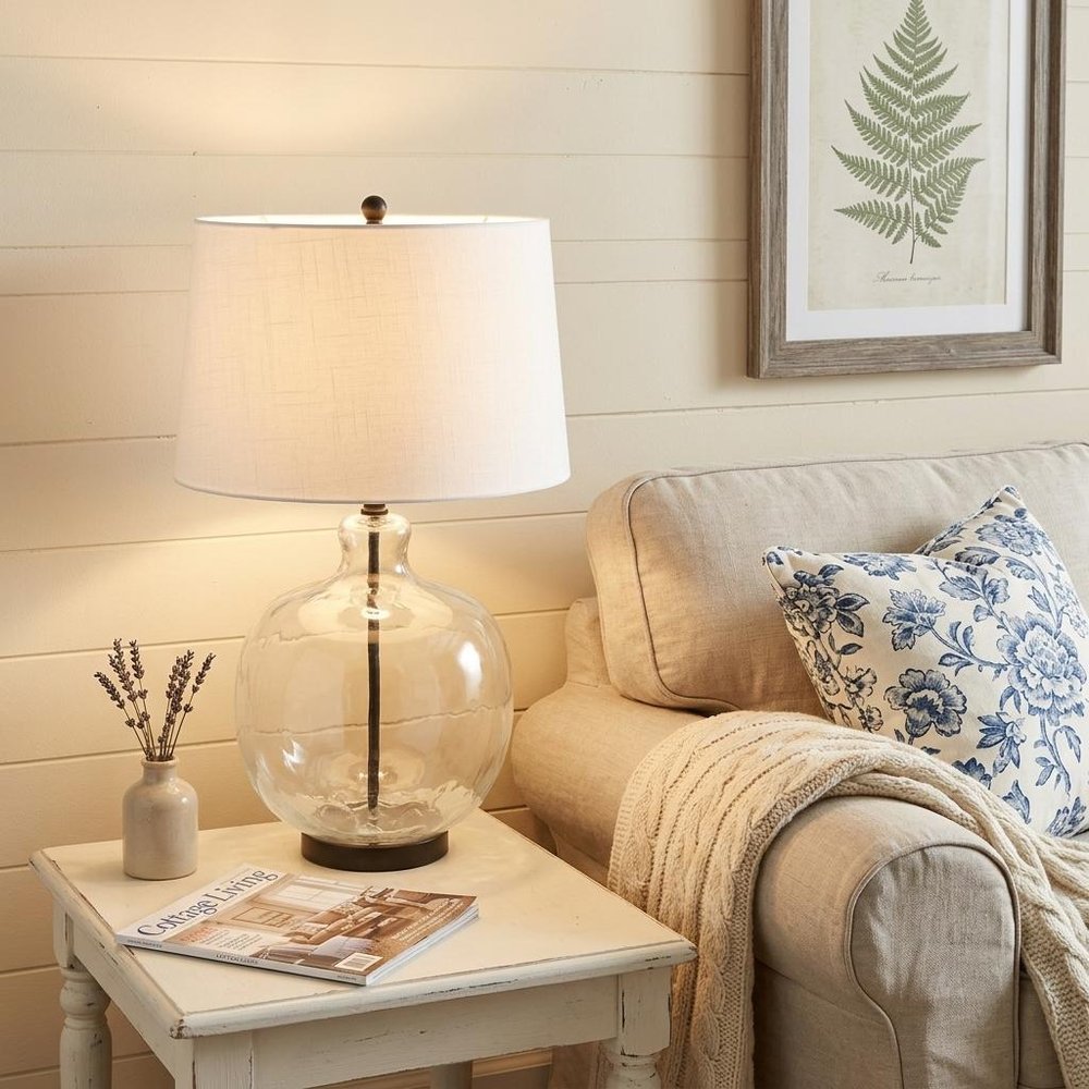 27" Black Globe Table Lamp With Globe Shade displayed on a wood tabletop in a furnished interior against a cream wall.