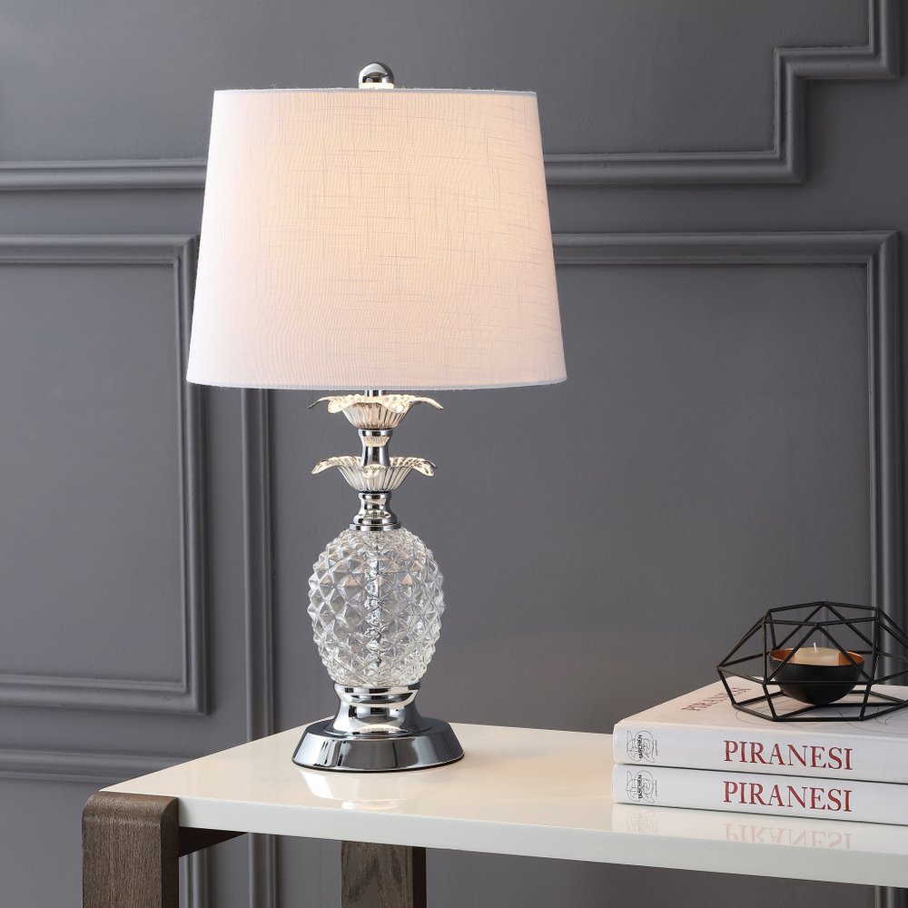 24" Silver Novelty Table Lamp With Drum Shade displayed on a tabletop in a furnished interior against a gray wall.