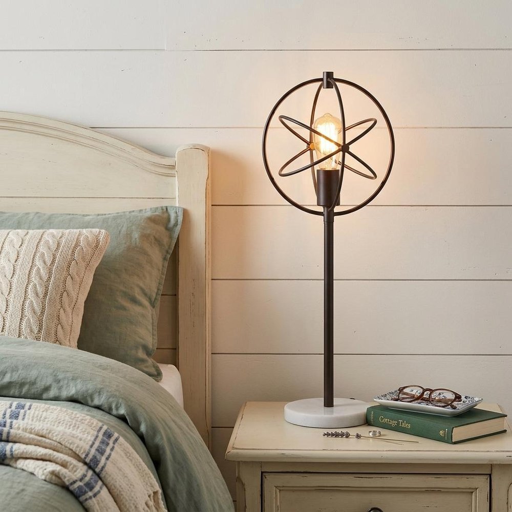 27" White Novelty Table Lamp With Globe Shade displayed on a wood tabletop in a furnished interior against a cream wall.