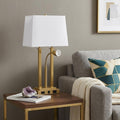24" Gold Swing Arm Novelty Table Lamp With Shade displayed on a dark wood tabletop in a furnished interior against a light gray wall.
