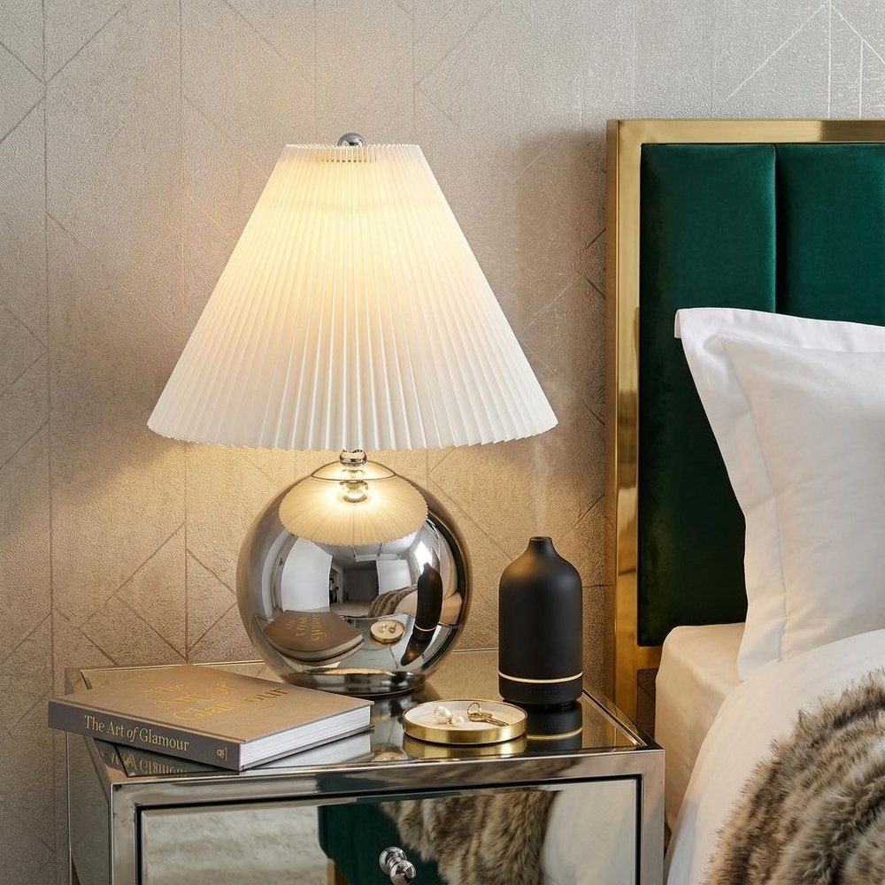 23" Silver Globe Lamp Base With Empire Shade styled in a furnished interior with a tan wall on a dark wood floor.