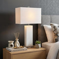 27" Clear Novelty Table Lamp With Shade displayed on a dark wood tabletop in a furnished interior against a gray wall.