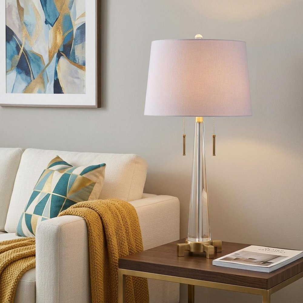 30" Gold Novelty Table Lamp With Empire Shade displayed on a dark wood tabletop in a furnished interior against a light gray wall.