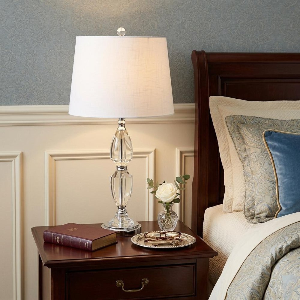27" Silver Novelty Bedside Lamp With Drum Shade styled in a furnished interior with a gray wall on a black floor.