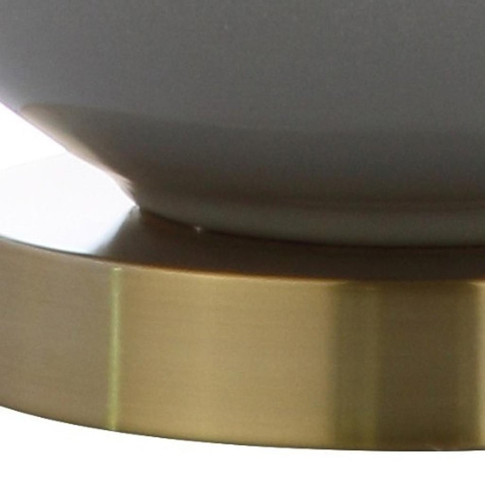 Cropped view of 25" Gold Novelty Table Lamp With Drum Shade focusing on the gold surface.