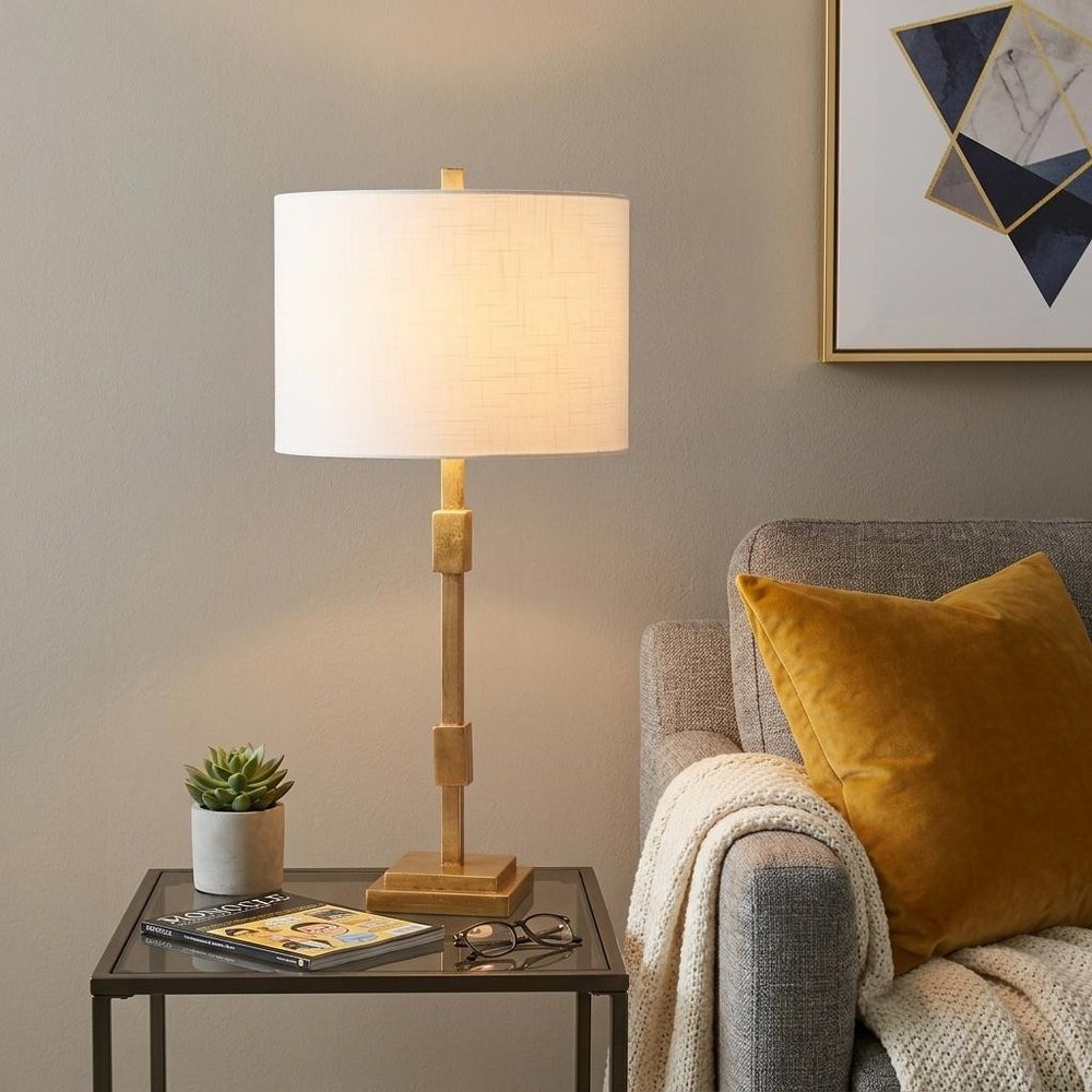 29" Gold Novelty Table Lamp With Globe Shade displayed on a wood tabletop in a furnished interior against a tan wall.