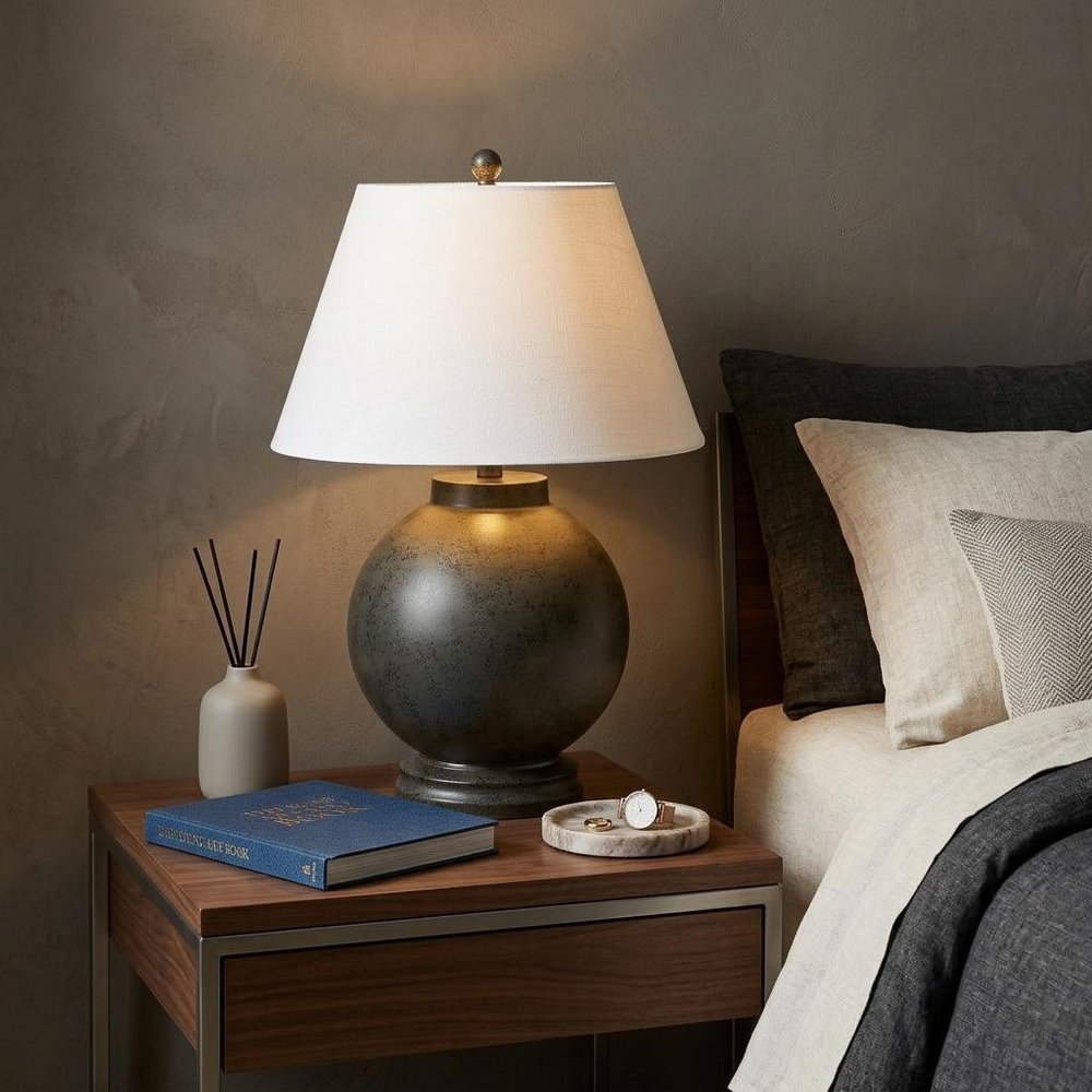 26" Dark Gray Novelty Table Lamp With Drum Shade displayed on a dark wood tabletop in a furnished interior against a dark brown wall in charcoal.
