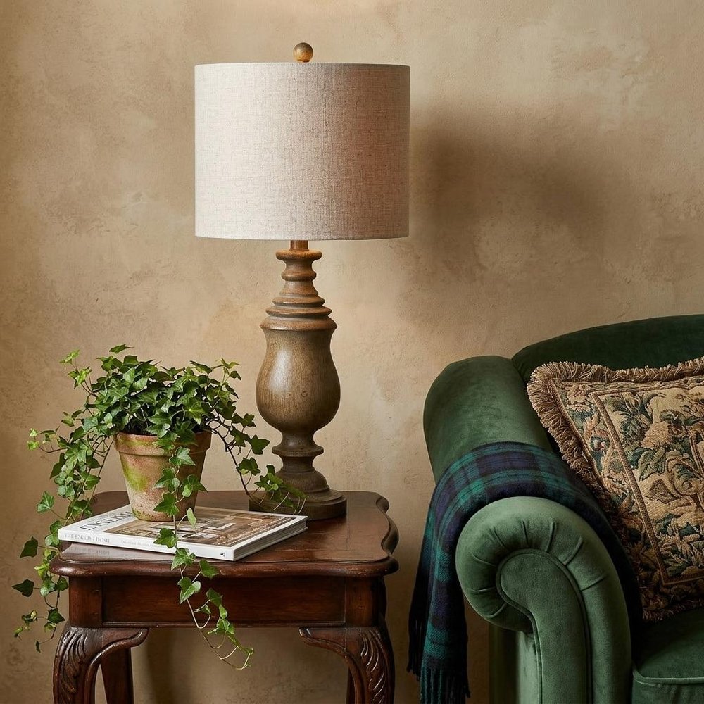 29" Brown Novelty Table Lamp With Globe Shade displayed on a dark wood tabletop in a furnished interior against a tan wall.