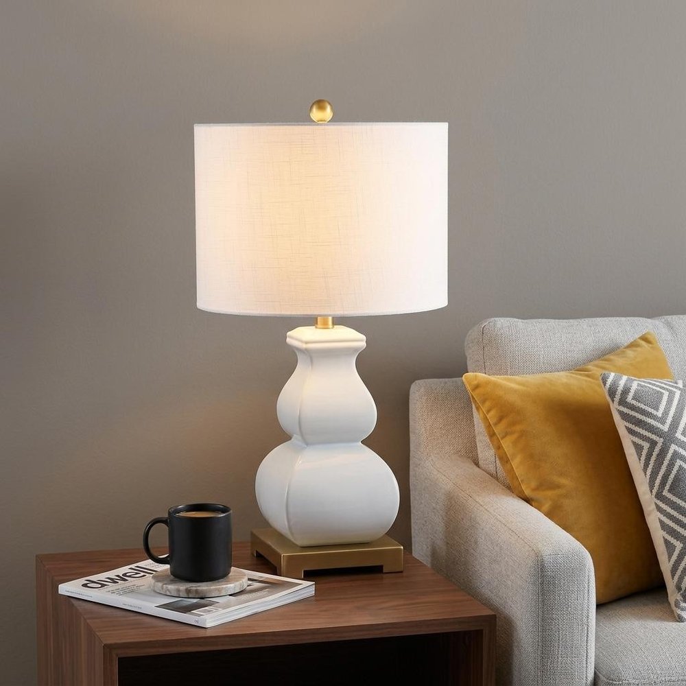 26" Gold Novelty Table Lamp With Globe Shade displayed on a dark wood tabletop in a furnished interior against a tan wall.