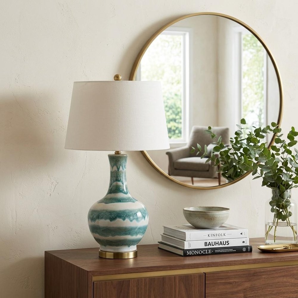 31" Gold Round Table Lamp With Globe Shade displayed on a dark wood tabletop in a furnished interior against an off-white wall.