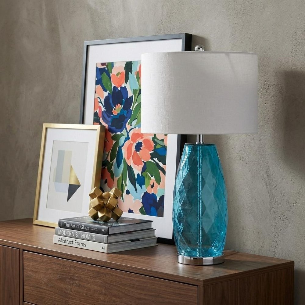 27" Silver Table Lamp With Drum Shade displayed on a dark wood tabletop in a furnished interior against a gray wall.