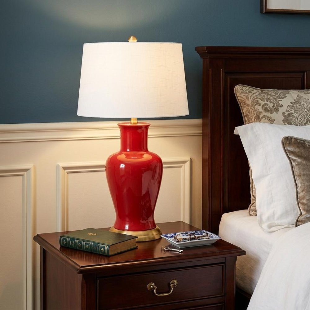 29" Red And Gold Urn Table Lamp With Drum Shade shown outdoors on an outdoor setting.