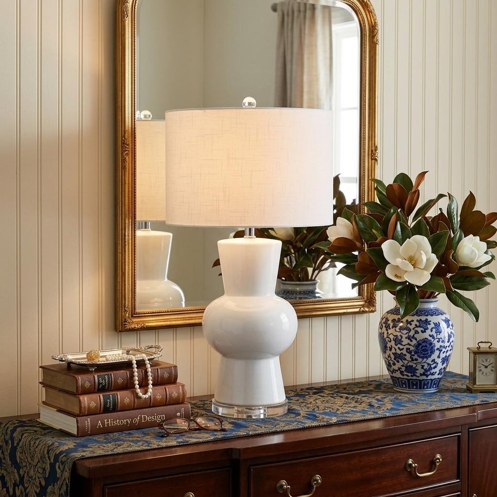 29" Clear Novelty Table Lamp With Drum Shade displayed on a tabletop in a furnished interior against a cream wall.