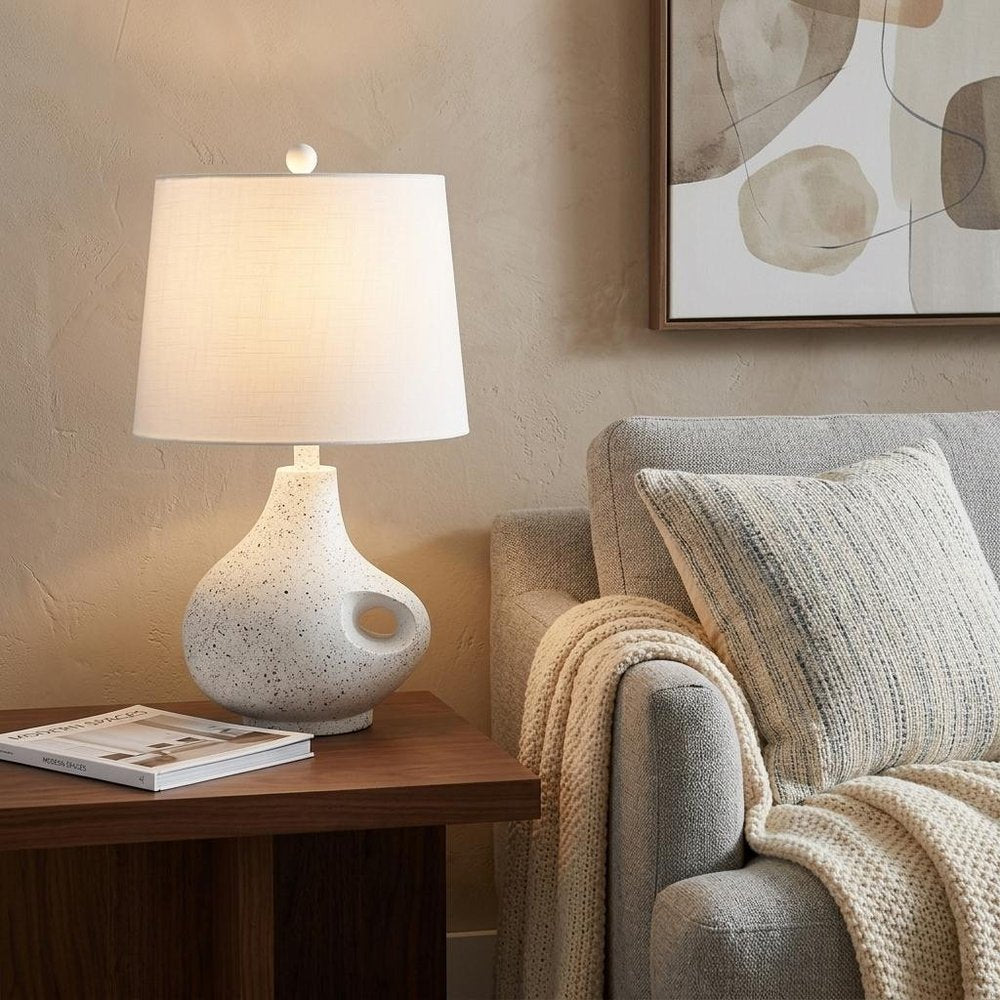 24" White Gourd Table Lamp With Novelty Shade displayed on a tabletop in a furnished interior against a tan wall.